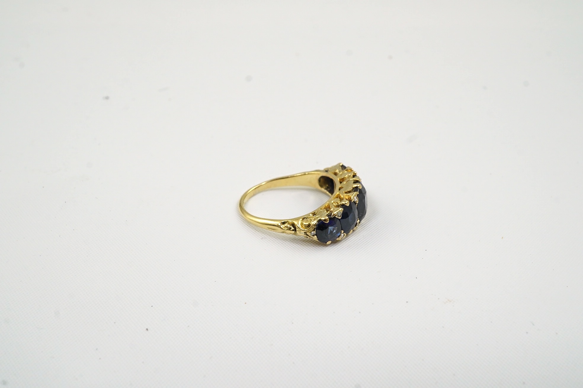 An Edwardian gold and graduated five stone oval cut sapphire set half hoop ring